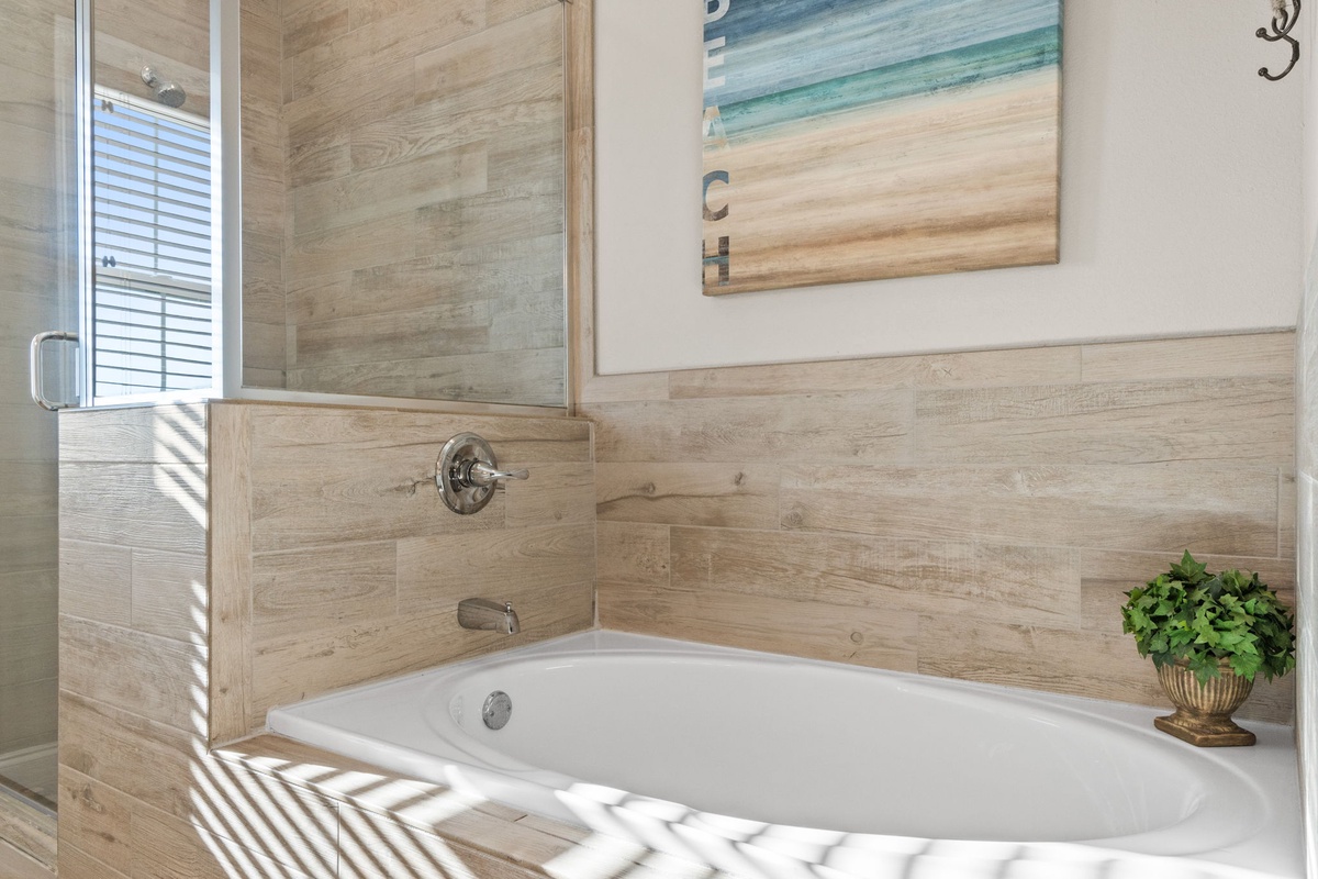 Soak in your private sanctuary, where warm wood tones and coastal artwork create a serene spa-like atmosphere in your luxurious bathroom retreat.