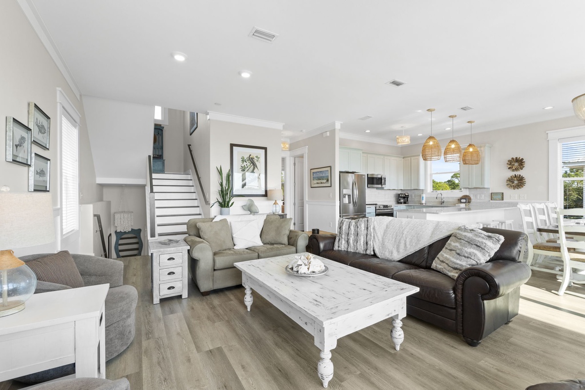 Relax in your spacious open-plan living area featuring coastal-chic furnishings, a gourmet kitchen, and warm pendant lighting perfect for unwinding.