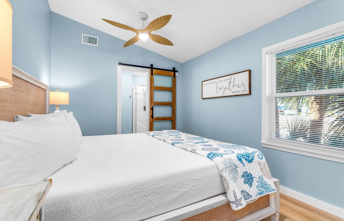 Drift into peaceful sleep in this coastal-inspired bedroom, where soft blue walls and tropical ceiling fan create your serene retreat.