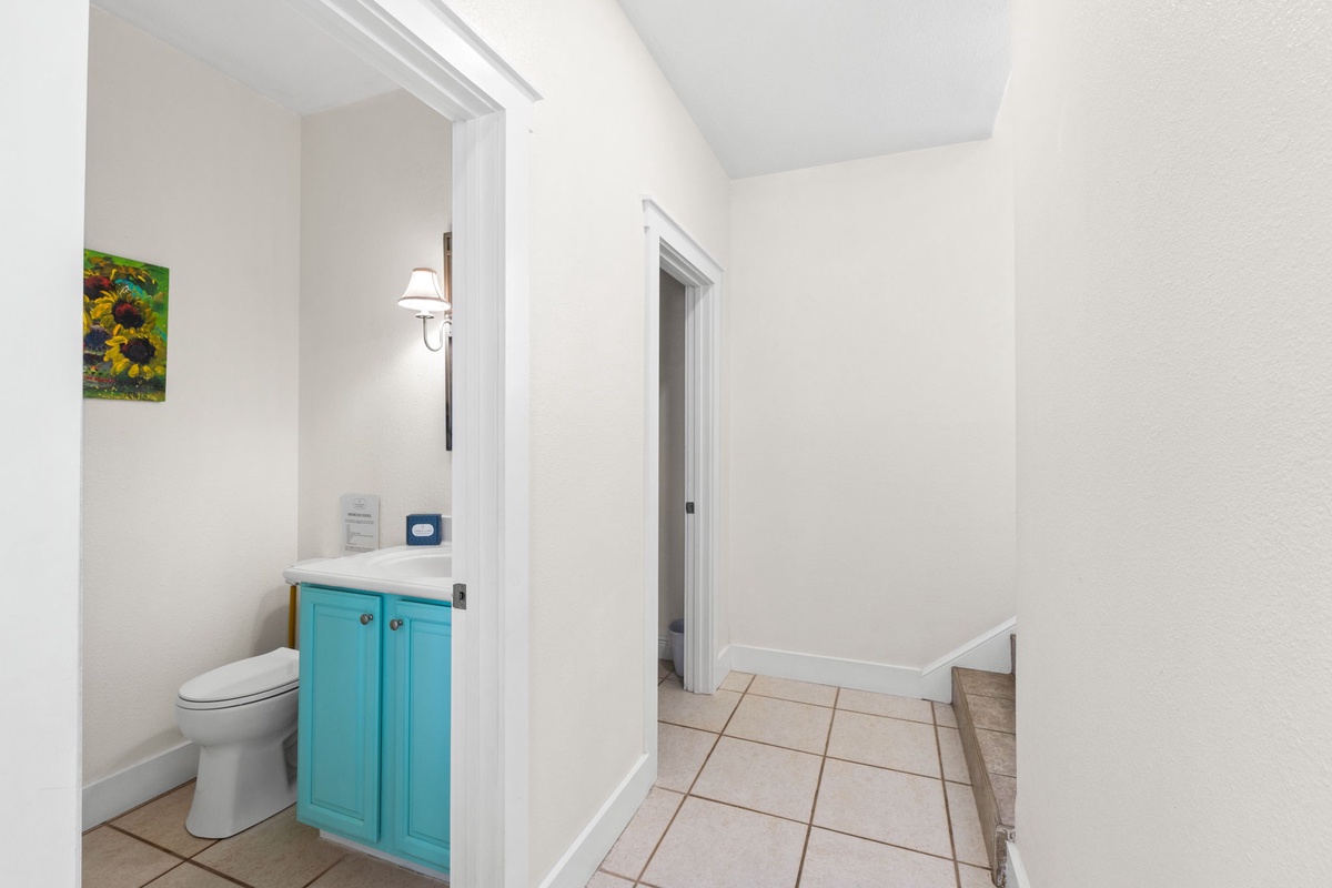 Bright, clean hallway connecting your bathroom to the rest of your space—featuring a cheerful turquoise vanity and soft lighting to make you feel right at home.