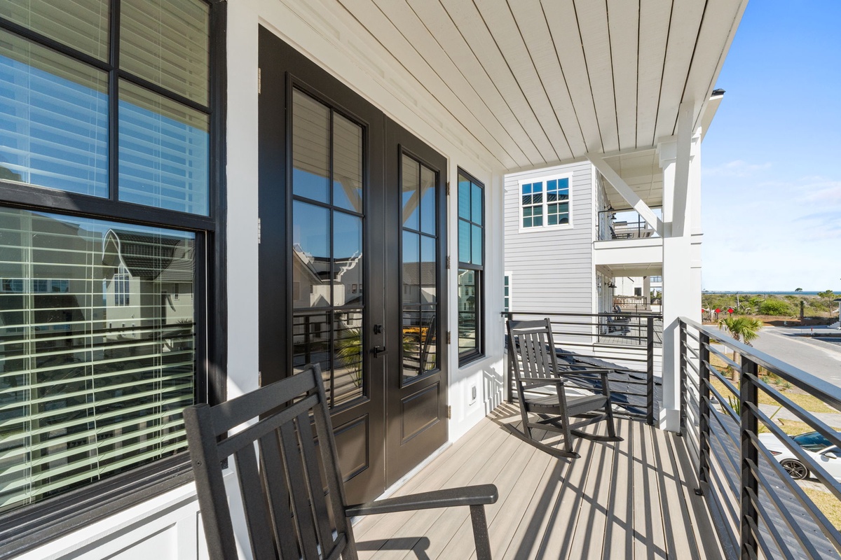 Relax on your private balcony with modern furniture and natural light streaming through elegant French doors.