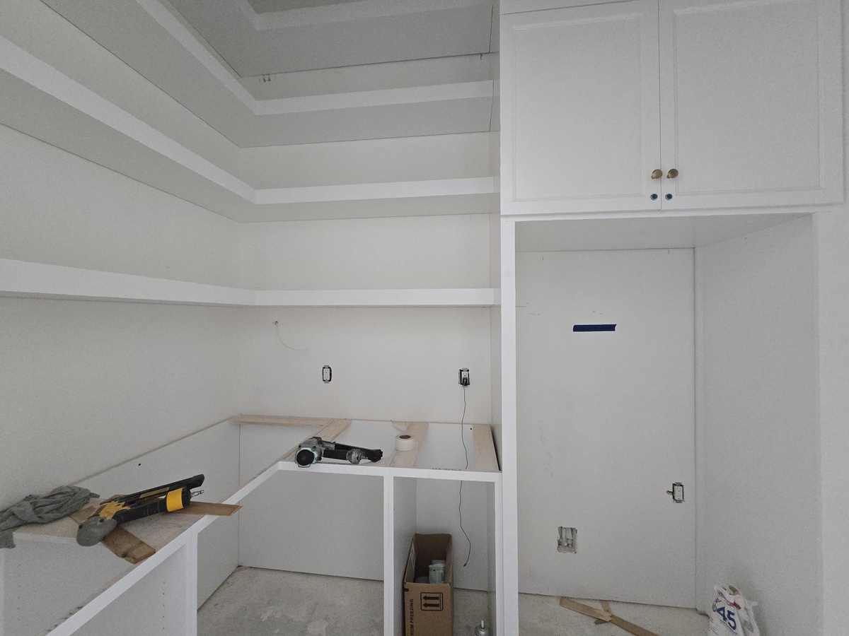 This space is mid-transformation, ready to become your personal retreat with fresh white cabinets and clean lines taking shape. Soon, you'll have ample storage and a bright, welcoming area to call your own.