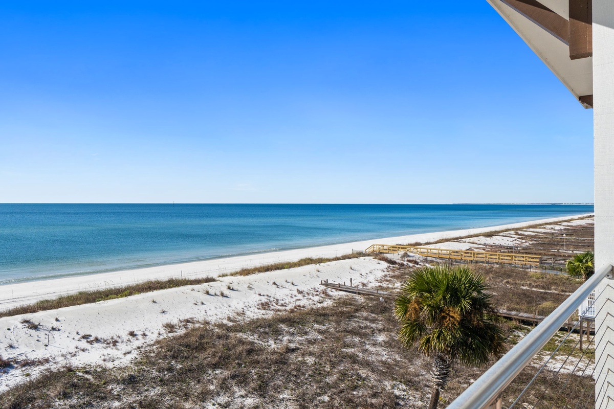 Stunning beachfront location with pristine white sand and turquoise waters stretching to the horizon under clear blue skies.