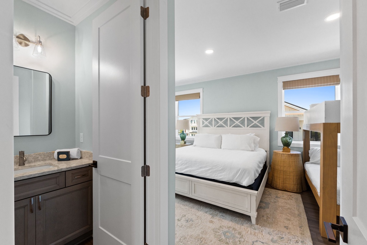 Step into your serene coastal bedroom, where crisp white linens and soft blue walls invite total relaxation. Natural light pours through the windows, framing your private retreat with glimpses of the surrounding neighborhood.