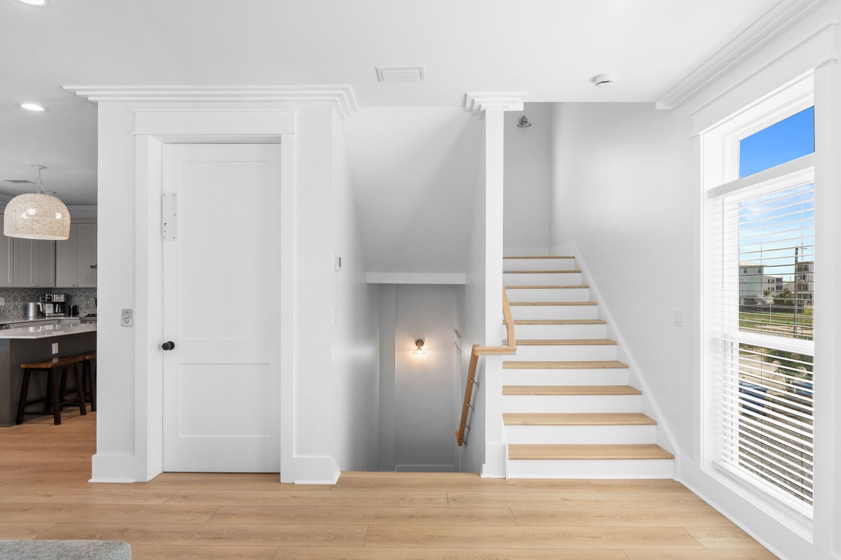 Bright, open living space with natural light pouring through plantation shutters and a modern staircase guiding your way to the upper level of your vacation retreat.