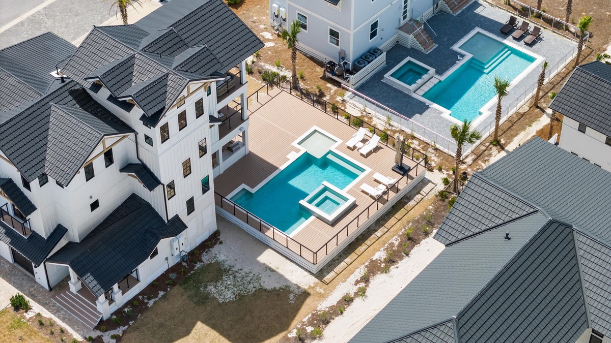 Aerial view of modern vacation rental properties featuring private pools surrounded by contemporary architecture and landscaping.