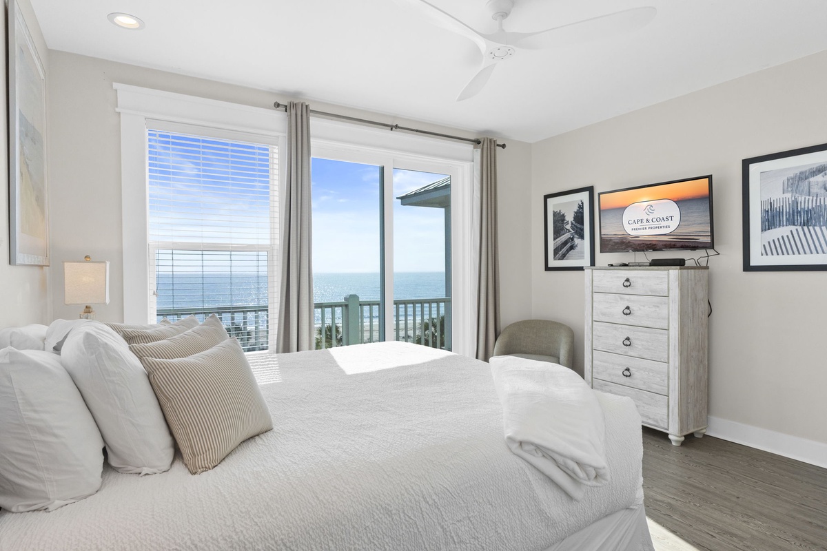 Wake up to stunning ocean views through your private balcony doors, where soft linens and peaceful coastal decor create the perfect seaside retreat.