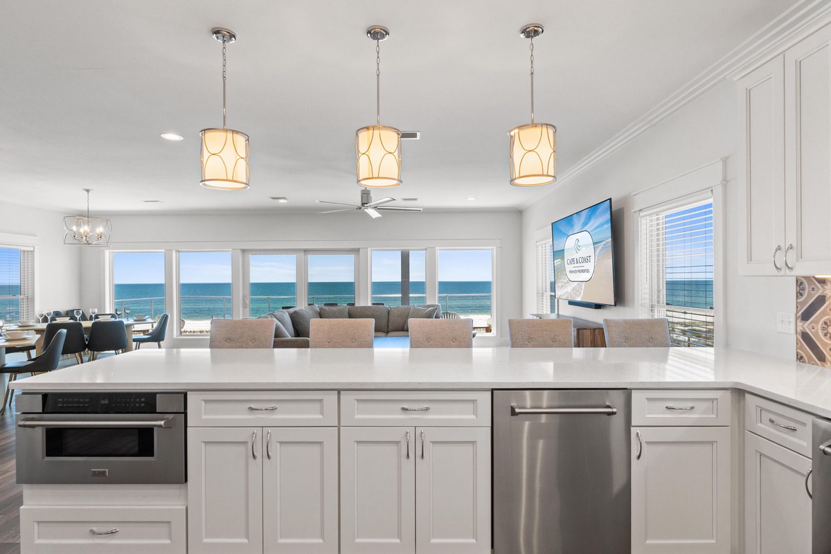 Your open kitchen flows into the dining and living areas, all framed by stunning sea views. Prepare meals at the spacious island while soaking in the turquoise horizon.