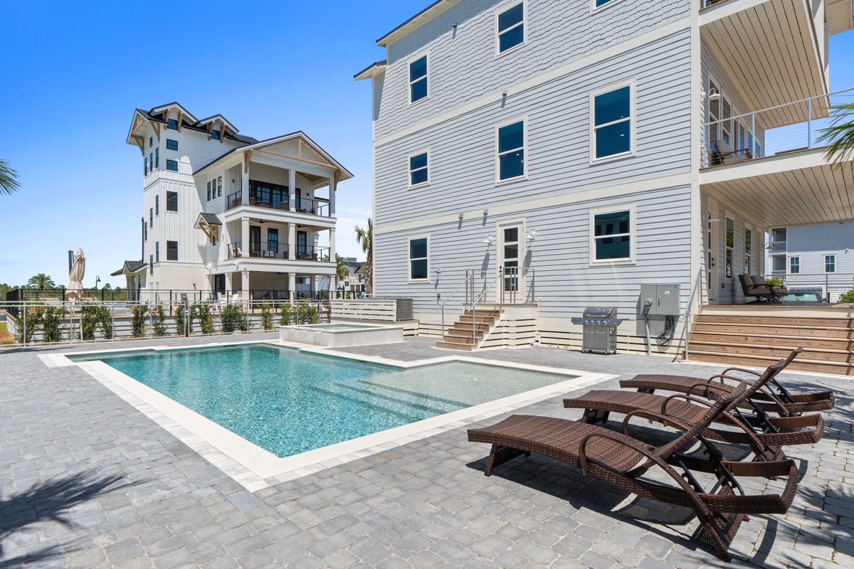 Your private backyard oasis awaits with a sparkling pool, sun loungers, and plenty of space to relax under clear blue skies.