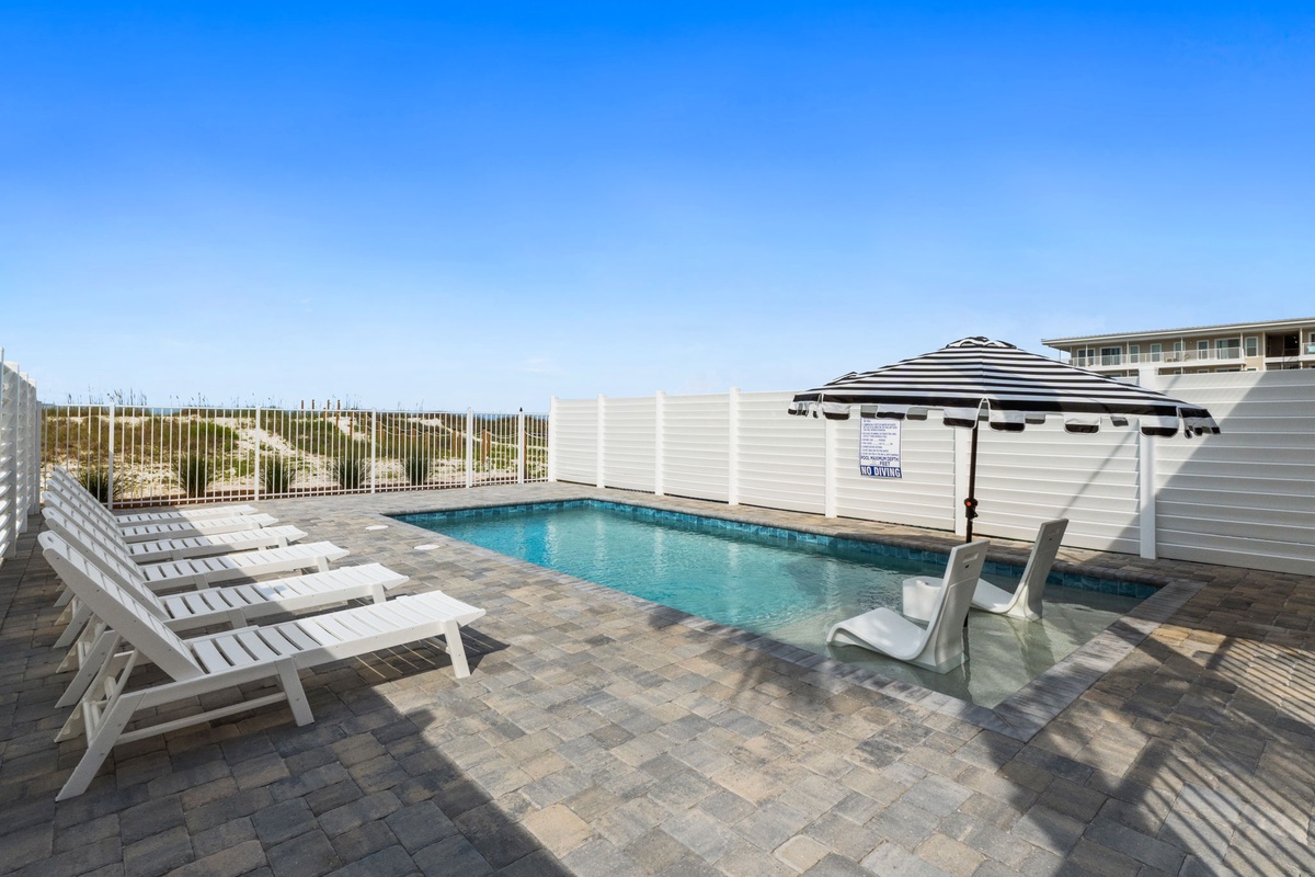 Your private pool awaits, framed by striped shade and sunlit loungers—perfect for lazy mornings and sunset dips just steps from the shore.