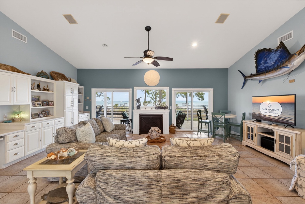 Relax in your coastal living room where ocean breezes meet comfort, featuring a cozy fireplace and stunning water views from your private balcony.