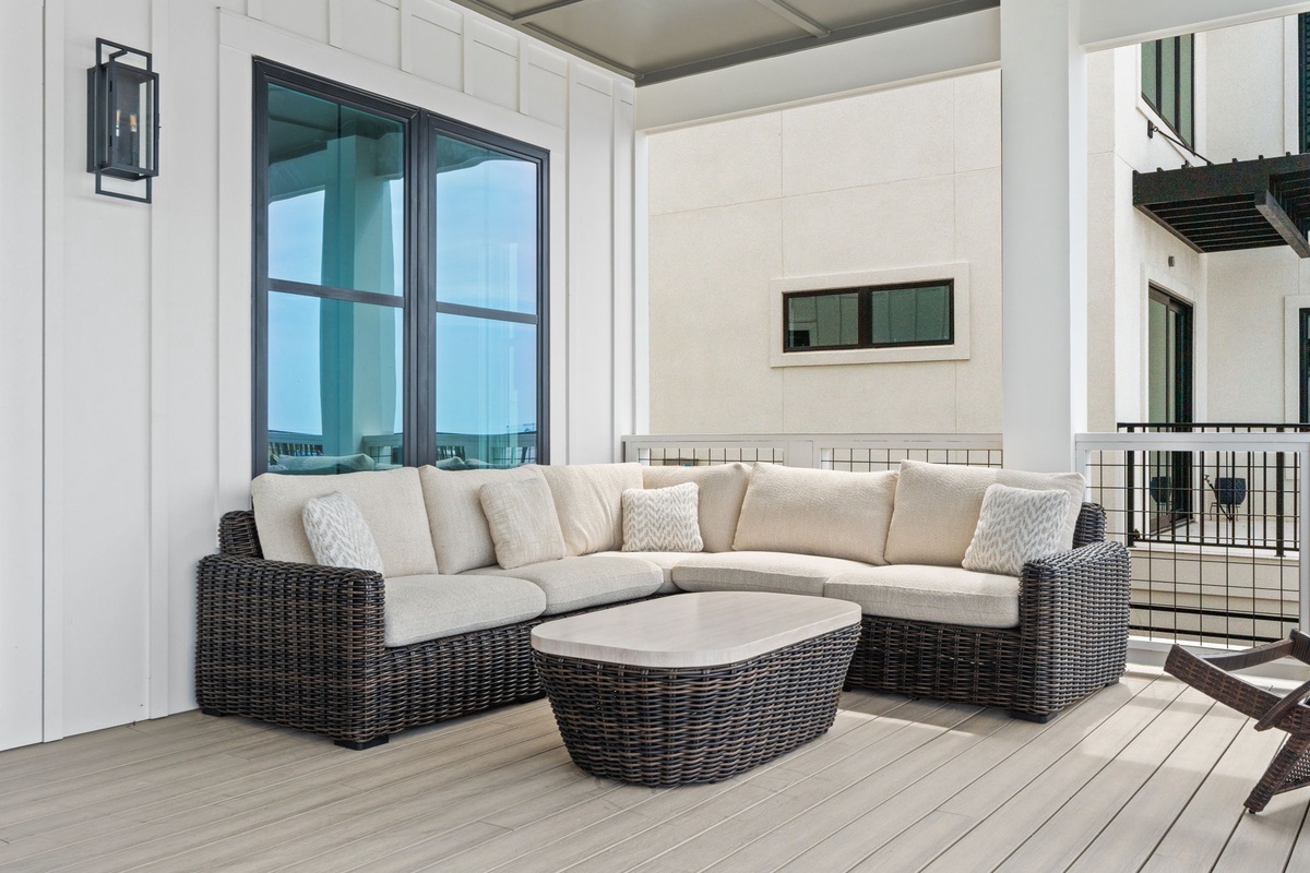 Unwind in your private outdoor living space with plush sectional seating, ocean glimpses through glass doors, and coastal breezes framing your coastal retreat.