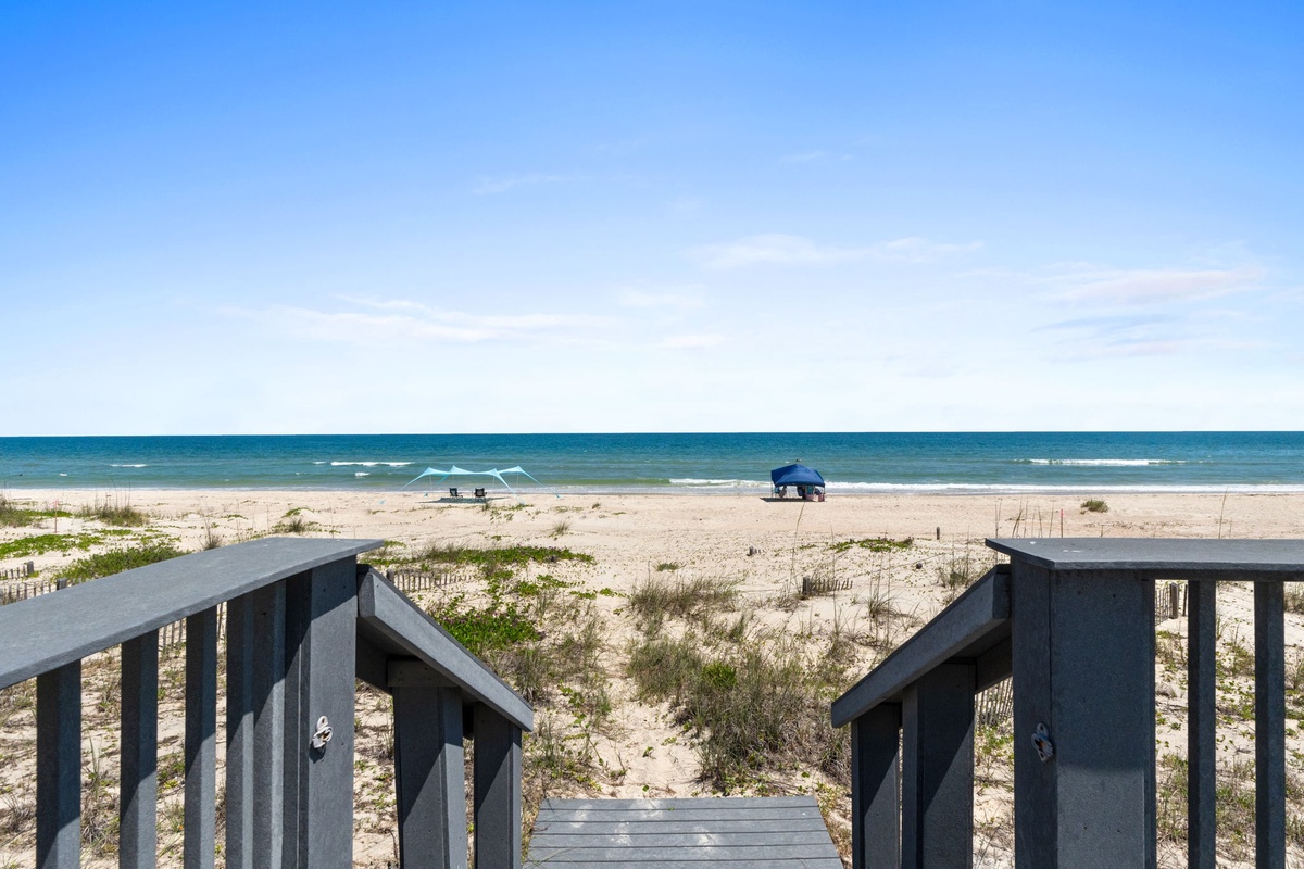Direct beach access from the property featuring a private boardwalk leading to pristine white sand and turquoise Gulf waters, with guest loungers and umbrellas positioned for seaside relaxation.