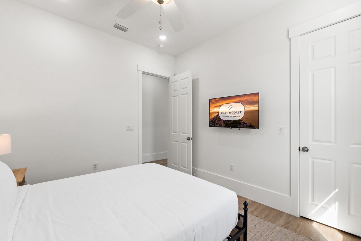 Unwind in your bright bedroom with crisp linens and wall-mounted TV for cozy movie nights after exploring.