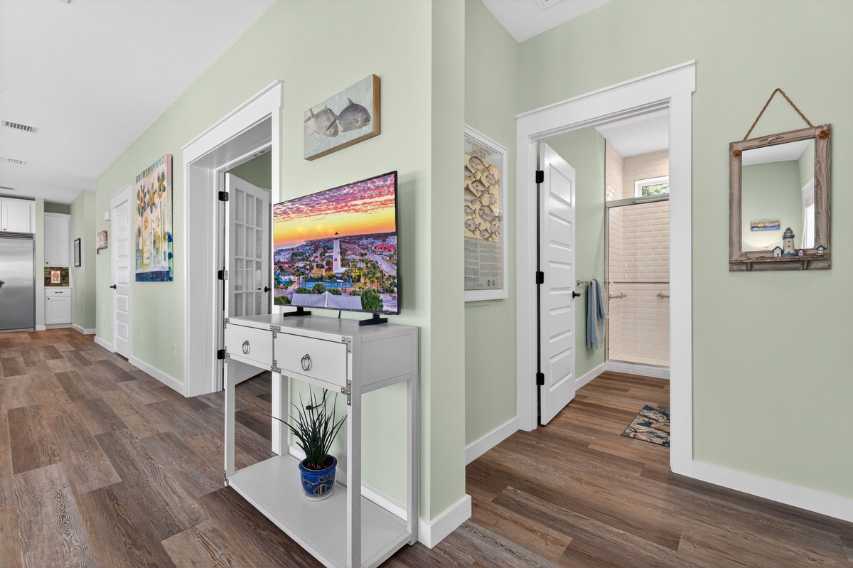 Bright hallway with calming sage walls, warm wood floors, and charming coastal décor—your peaceful connection between rooms awaits.
