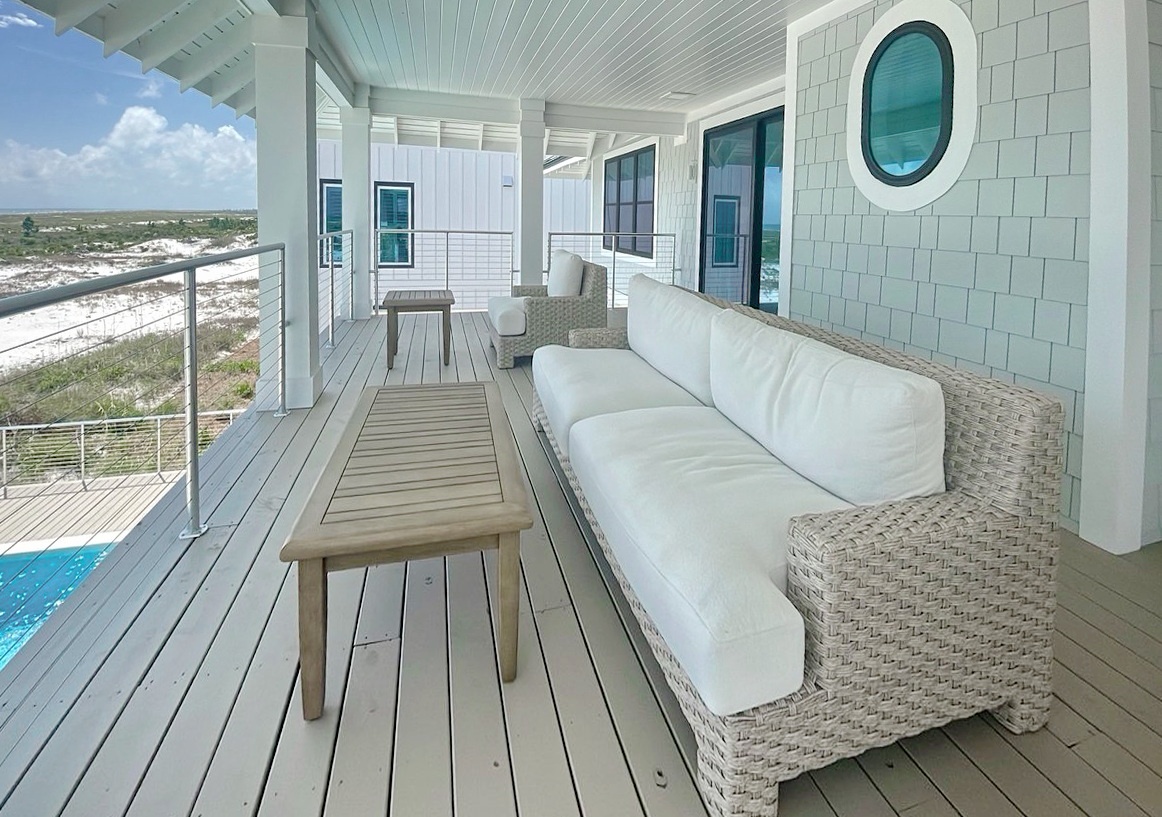 A coastal retreat perched above sandy dunes and natural landscape, featuring a private pool and comfortable covered deck for enjoying the beach surroundings.