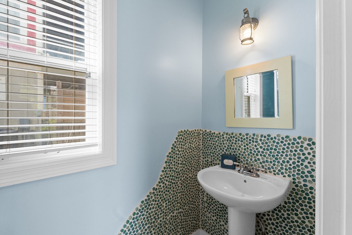 Freshen up in your coastal-inspired powder room, where soothing blue walls meet vibrant mosaic tile. Natural light from the window brightens your space, creating a calm, cheerful atmosphere.