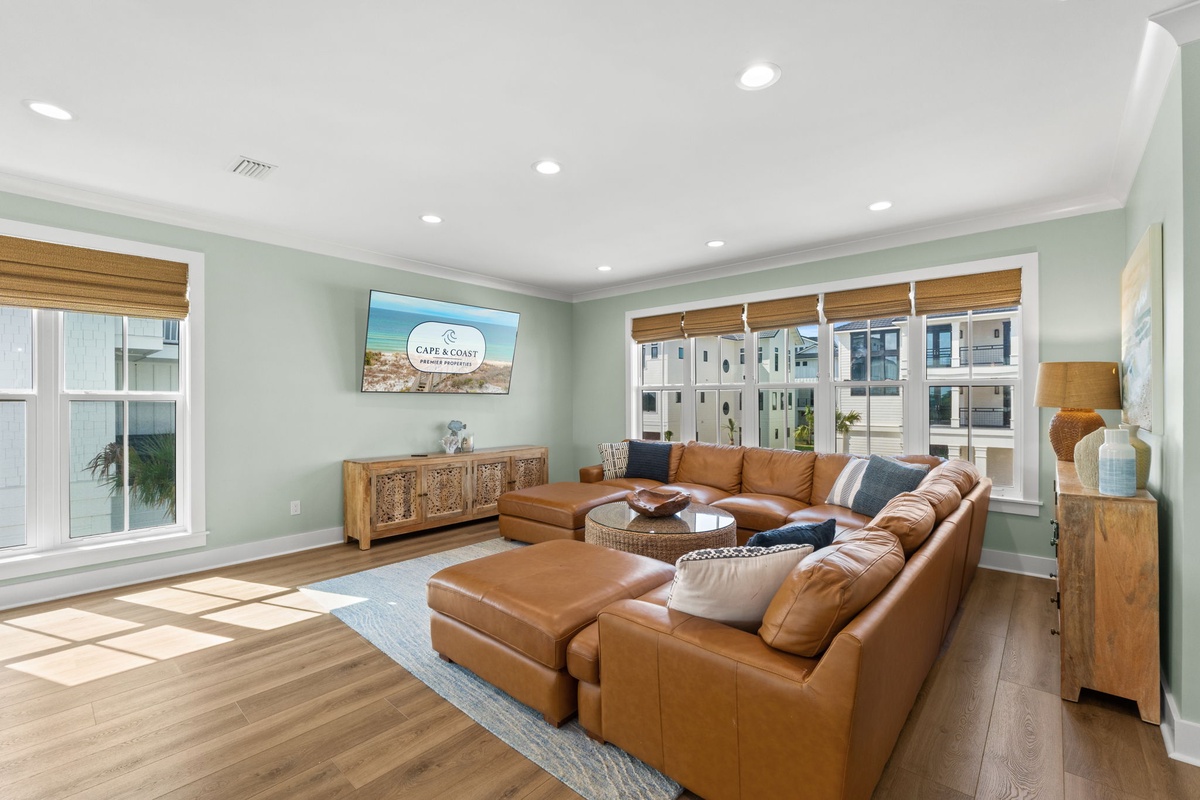 Sink into supple leather sofas and let sunlight stream through your windows as you relax in this coastal-inspired living room, thoughtfully designed with bamboo shades and serene sea-foam walls.