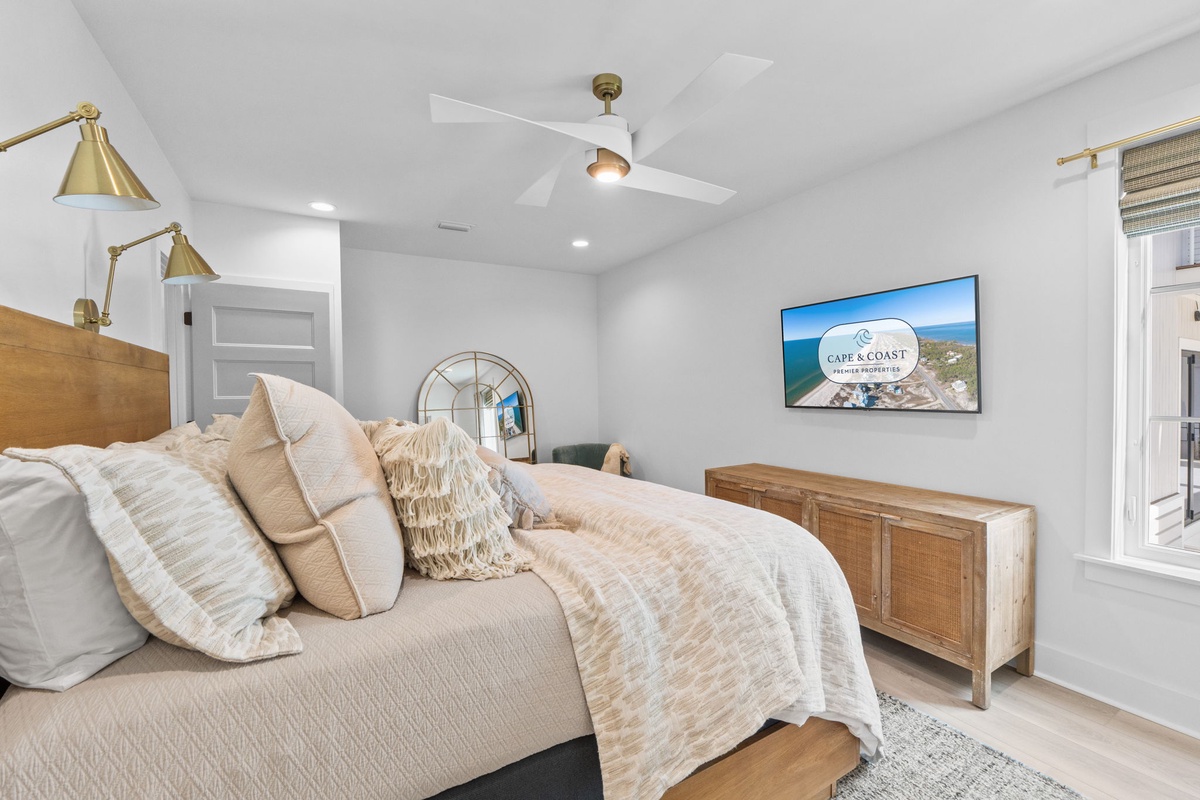 Sink into coastal comfort in your serene bedroom featuring plush bedding, stylish brass accents, and modern amenities for perfect relaxation.