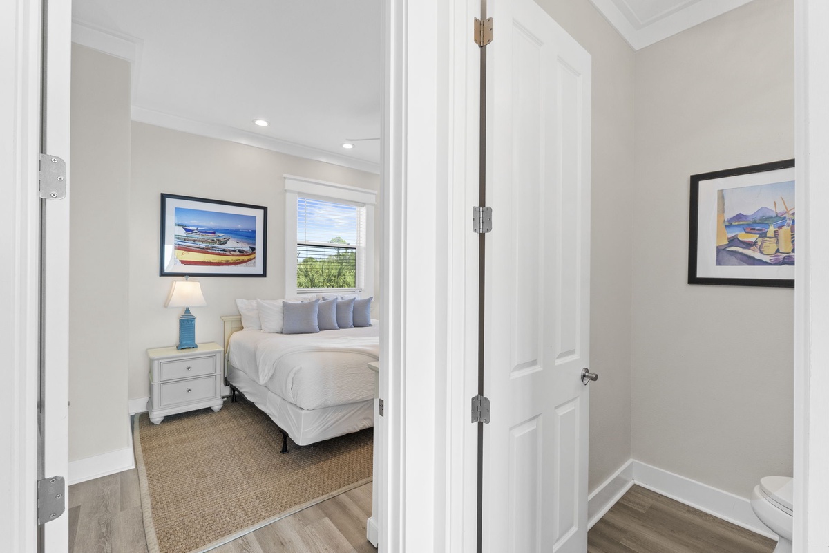 Step into your serene bedroom sanctuary with coastal artwork and soft linens, complete with a private bathroom for ultimate comfort.
