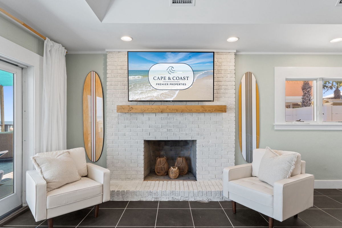Your living room features coastal-chic decor with cozy seating by a charming fireplace, beach-inspired accents, and a large TV perfect for unwinding after sun-soaked days by the shore.
