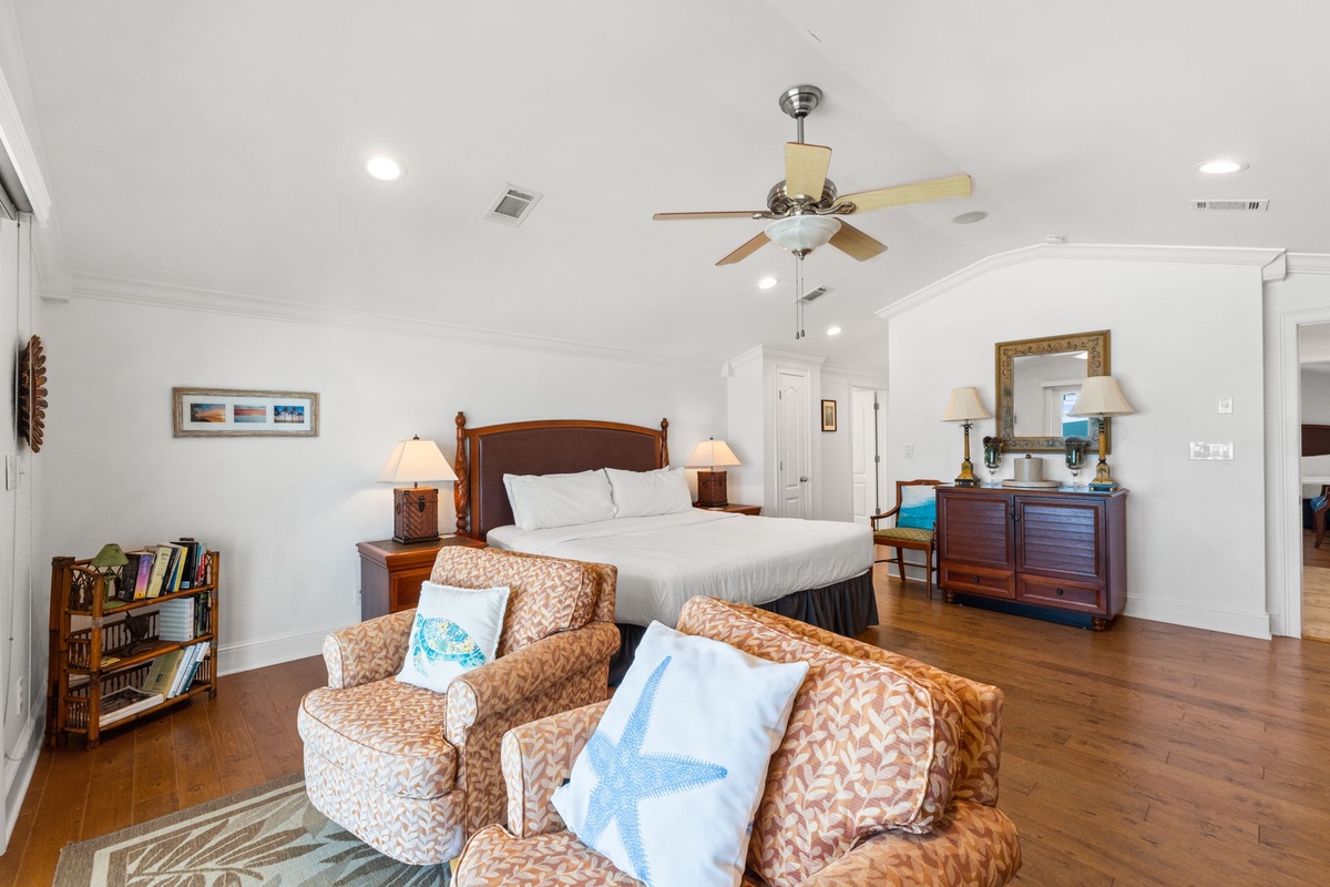 Unwind in your spacious suite where coastal charm meets comfort—plush seating, a king bed with crisp linens, warm wood tones, and high ceilings create your perfect retreat.