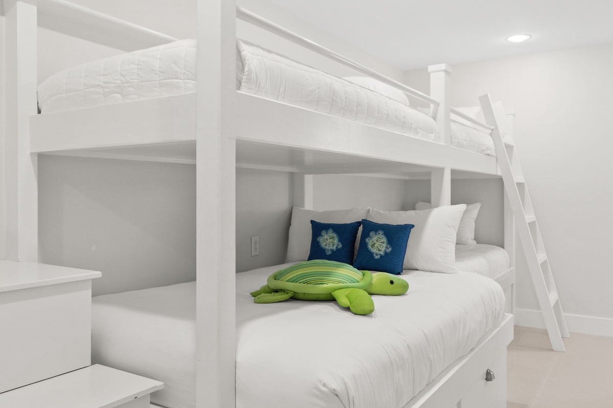 Your kids will love this charming bunk bed setup with playful turtle friend and nautical-themed pillows in the pristine white bedroom.