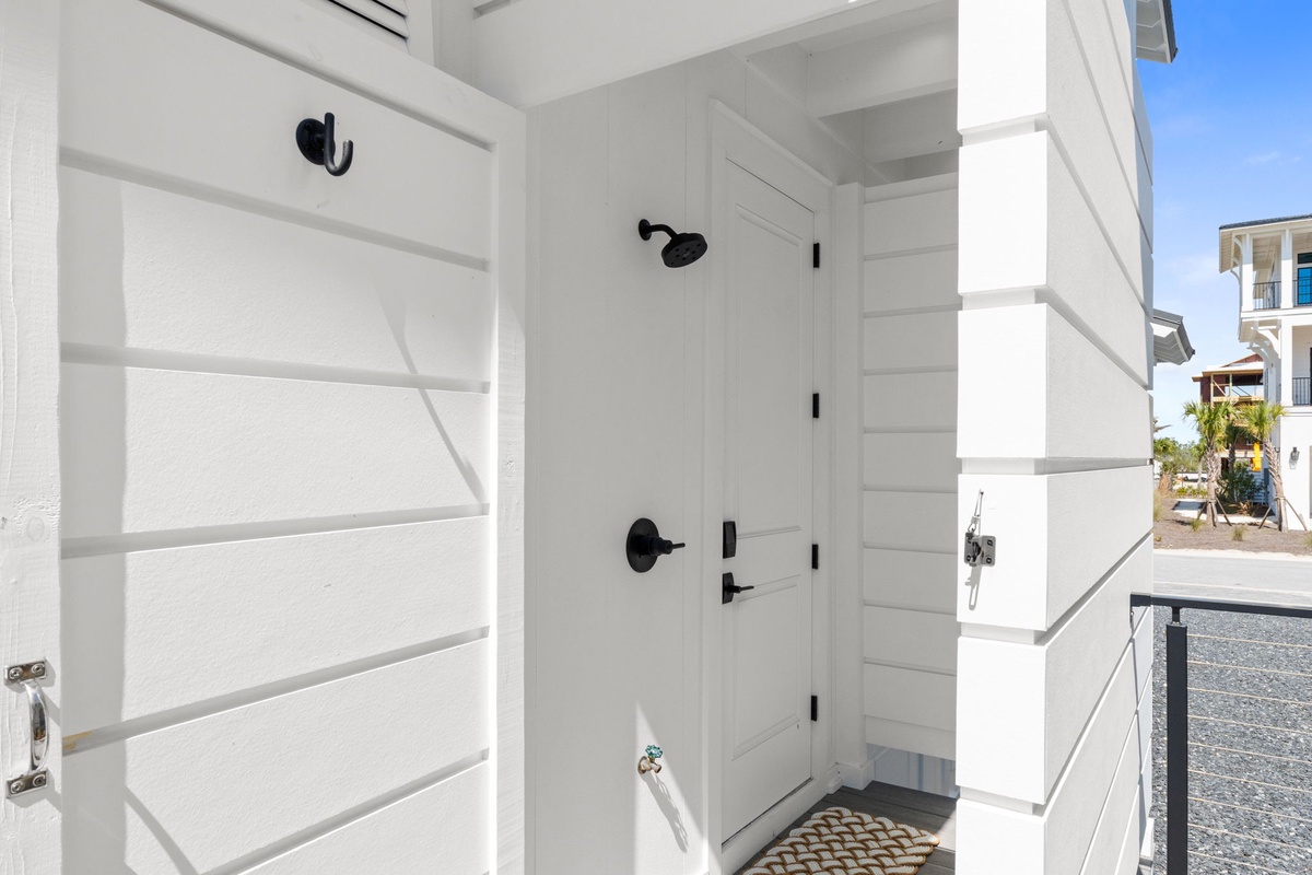 A bright outdoor shower area with crisp white finishes and coastal charm—perfect for rinsing off after beach days.