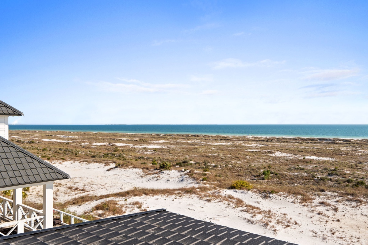 Pristine coastal landscape stretches toward turquoise waters, with natural dunes and vegetation creating a peaceful seaside setting.