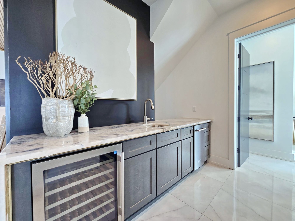 Your elegant wet bar awaits with marble counters, wine storage, and sleek cabinetry perfect for entertaining.