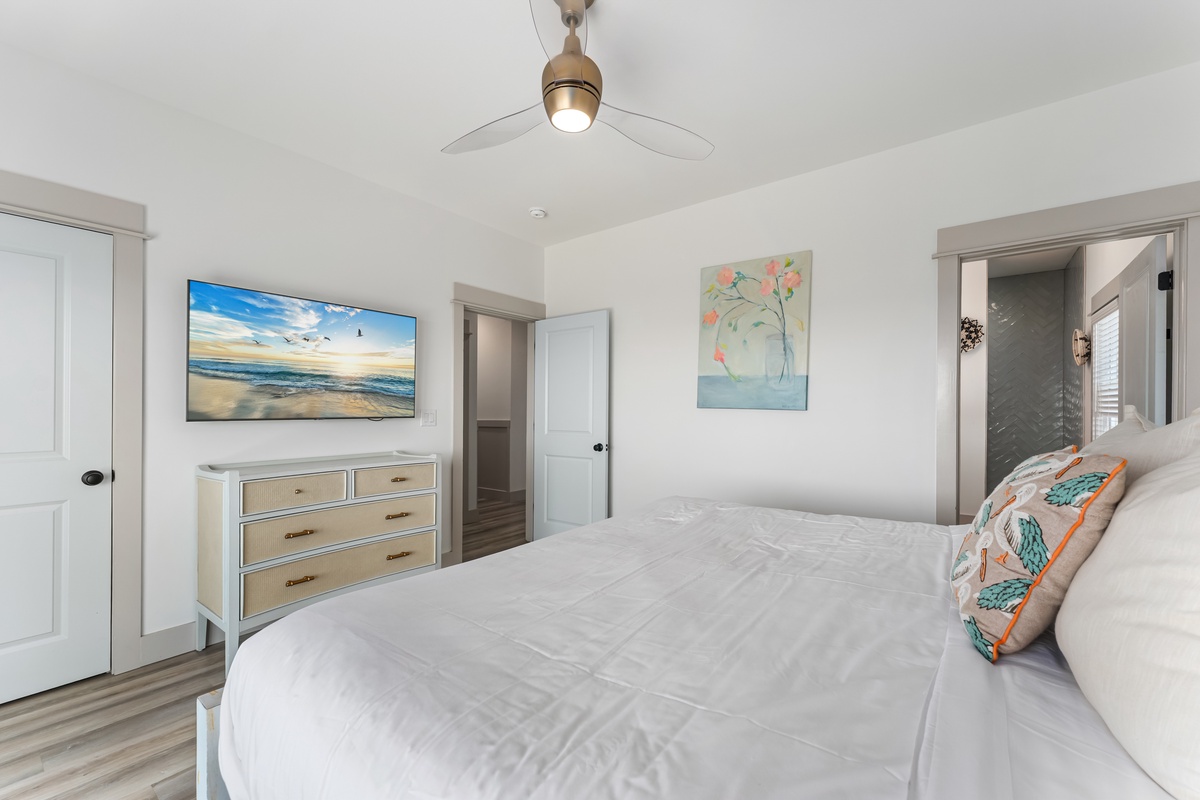 Drift off peacefully in your bright bedroom with coastal-themed artwork, a large TV for relaxing evenings, and an en-suite bathroom for your convenience.