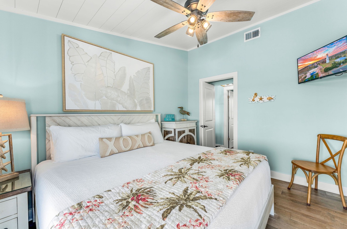 Drift off in your serene coastal bedroom with soft aqua walls, tropical bedding, and gentle ceiling fan creating perfect sleeping comfort.