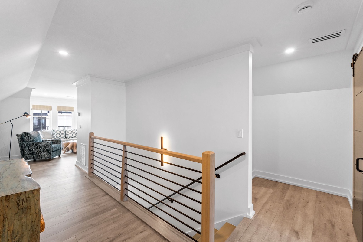 Modern loft with sleek stairway railing, warm wood floors, and bright open layout perfect for relaxing after exploring the area.