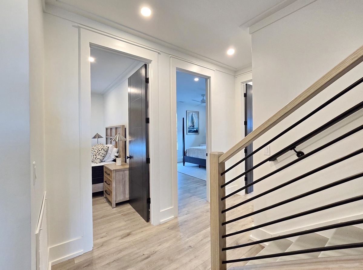 Your private hallway connects beautifully appointed spaces with modern railings and warm wood floors throughout.