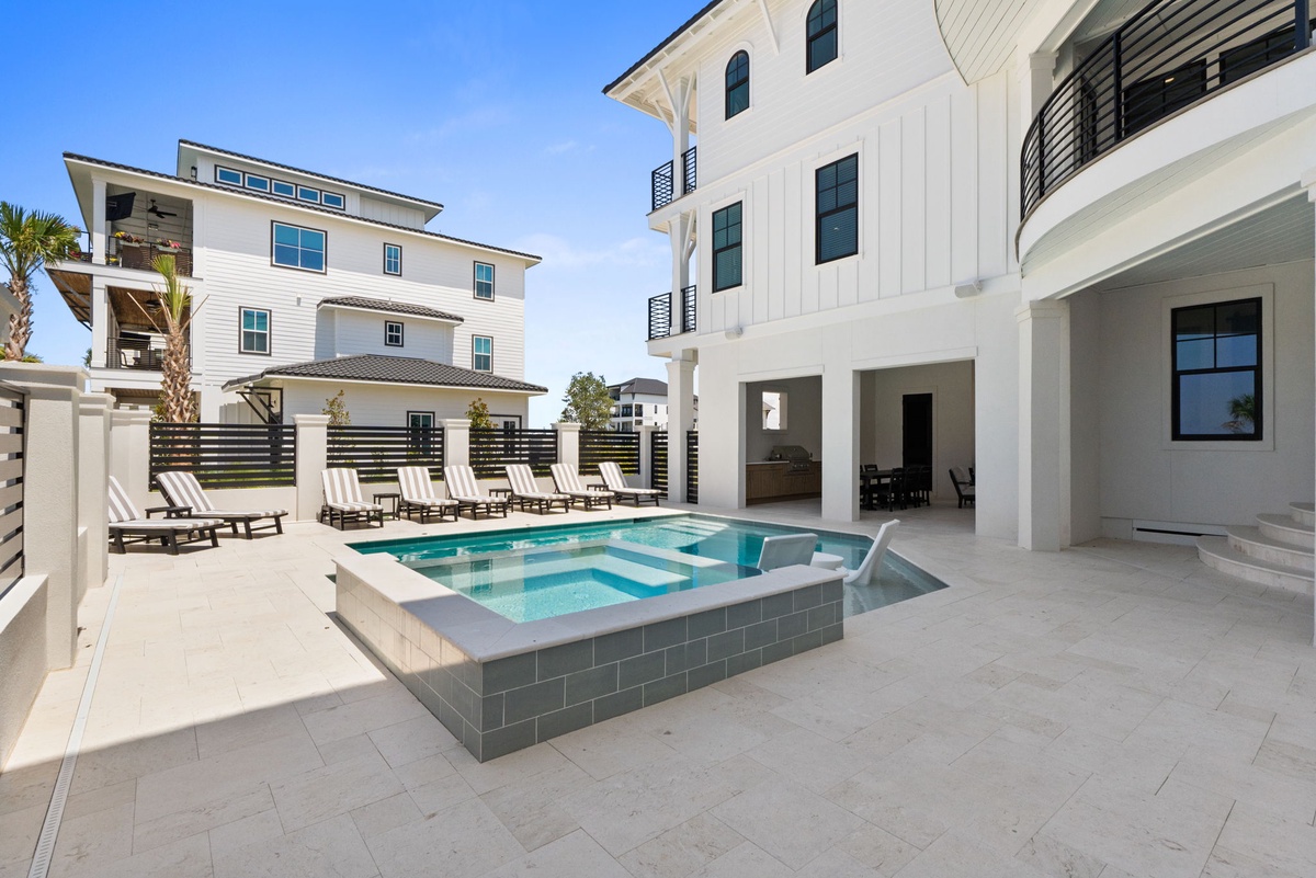Modern coastal retreat featuring a sparkling pool and hot tub, surrounded by pristine white architecture and multiple private balconies under sunny blue skies.