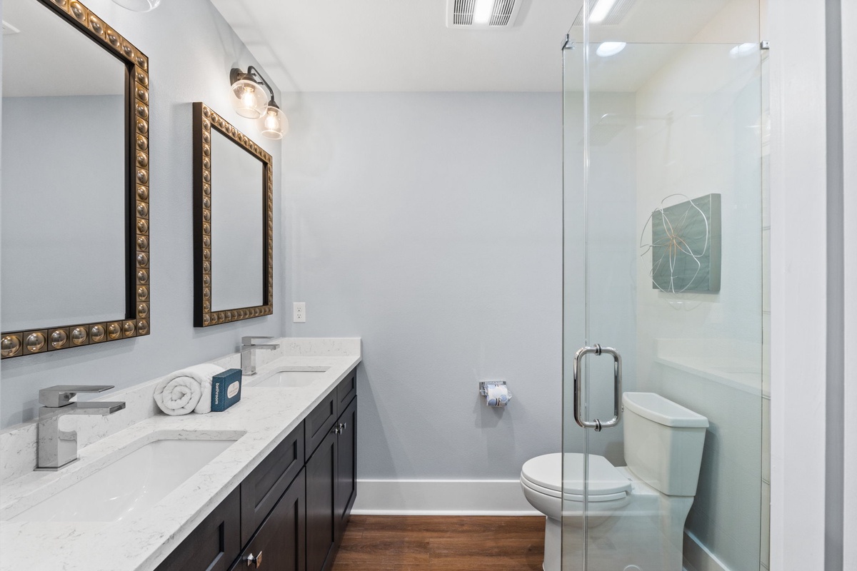 Freshen up in your modern bathroom with dual vanities, elegant mirrors, and a sleek glass-enclosed shower—your private retreat awaits.