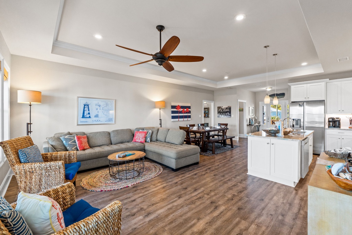 Relax in your open-concept living space with plush sectional seating, modern kitchen, and coastal touches throughout.