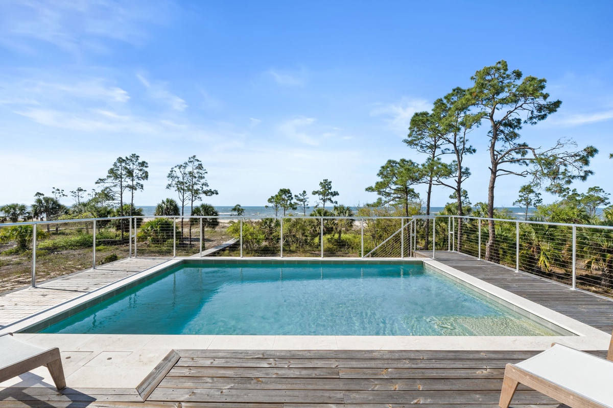 Sparkling pool surrounded by coastal pines with stunning natural landscape views stretching to the horizon.