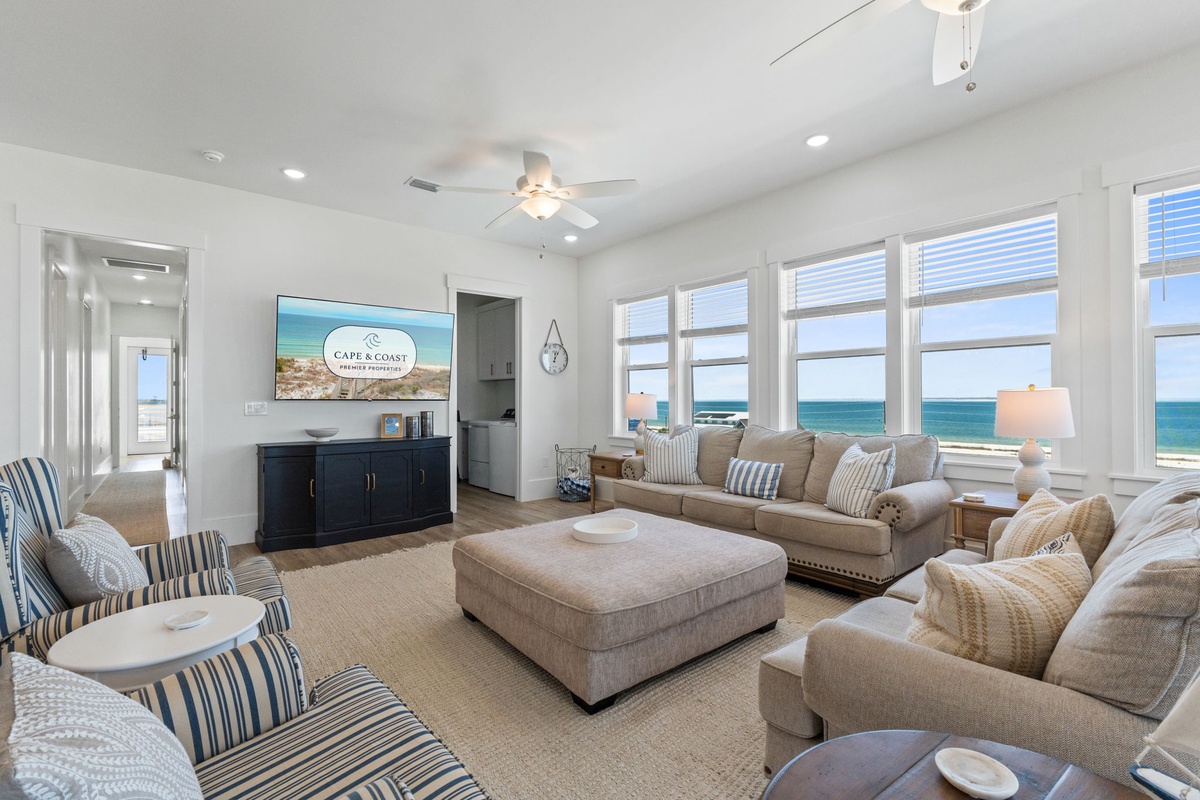 Sink into plush sofas while enjoying panoramic ocean views through floor-to-ceiling windows in this elegant coastal living room.