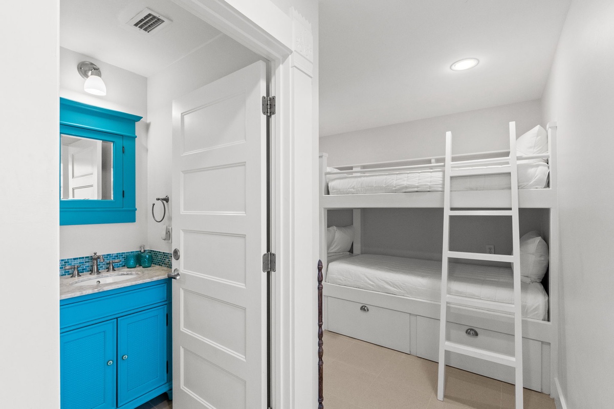 Your kids will love this cozy bunk room with built-in beds and cheerful turquoise bathroom - perfect for family adventures and bedtime stories.