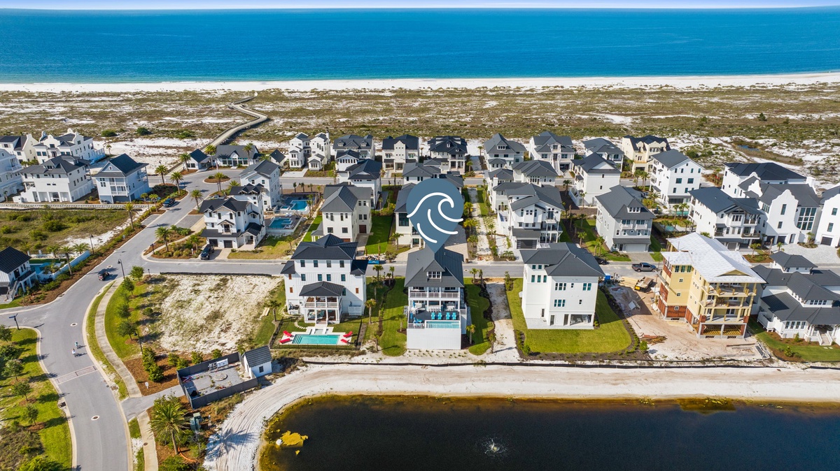 Aerial view of a charming beachfront community featuring coastal homes nestled between pristine white sand beaches and serene waterfront surroundings.