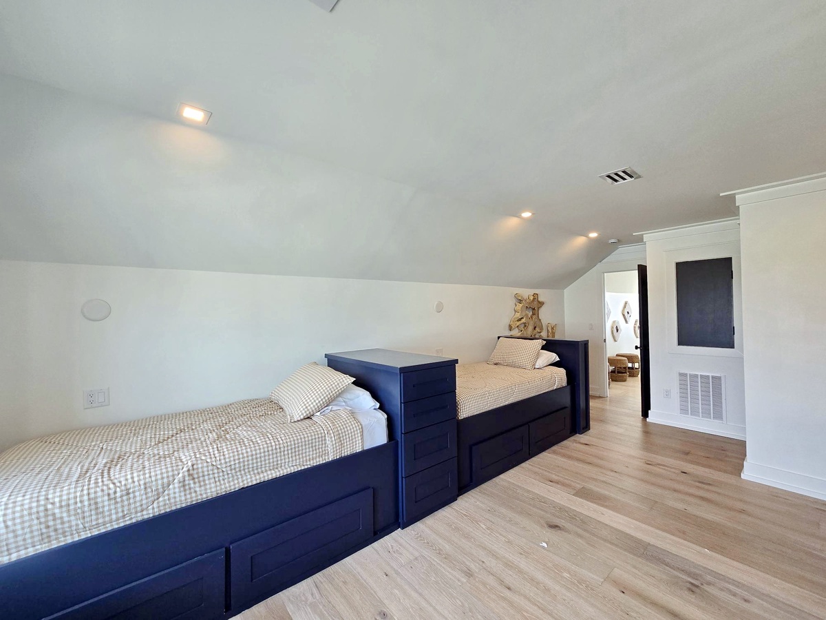 Cozy attic bedroom with twin beds offers your group comfortable rest under slanted ceilings and warm lighting.