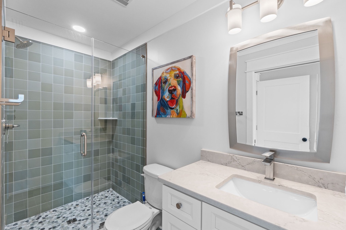 Refresh in your private bathroom featuring a spacious walk-in shower with sea-glass tiling, modern vanity with marble countertop, and cheerful touches that make it feel like home.