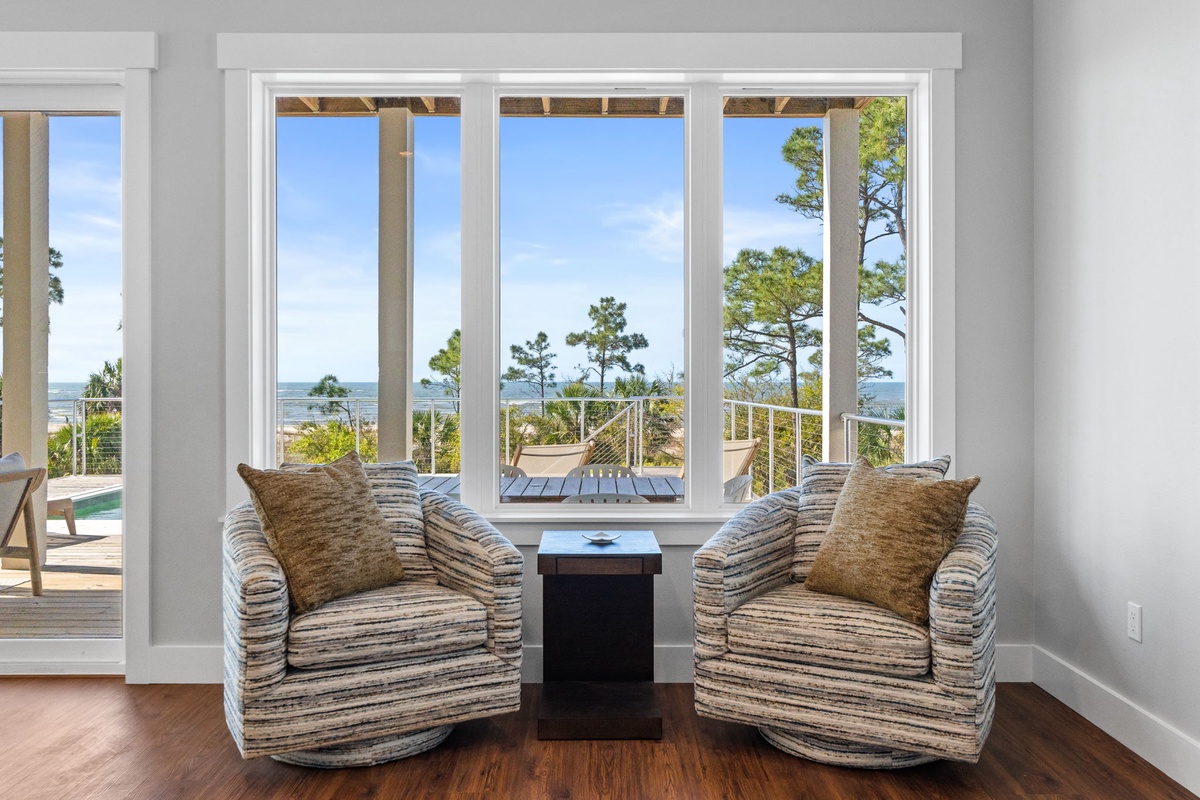 Sink into plush swivel chairs and soak up stunning ocean views through floor-to-ceiling windows that frame the coastal paradise beyond.