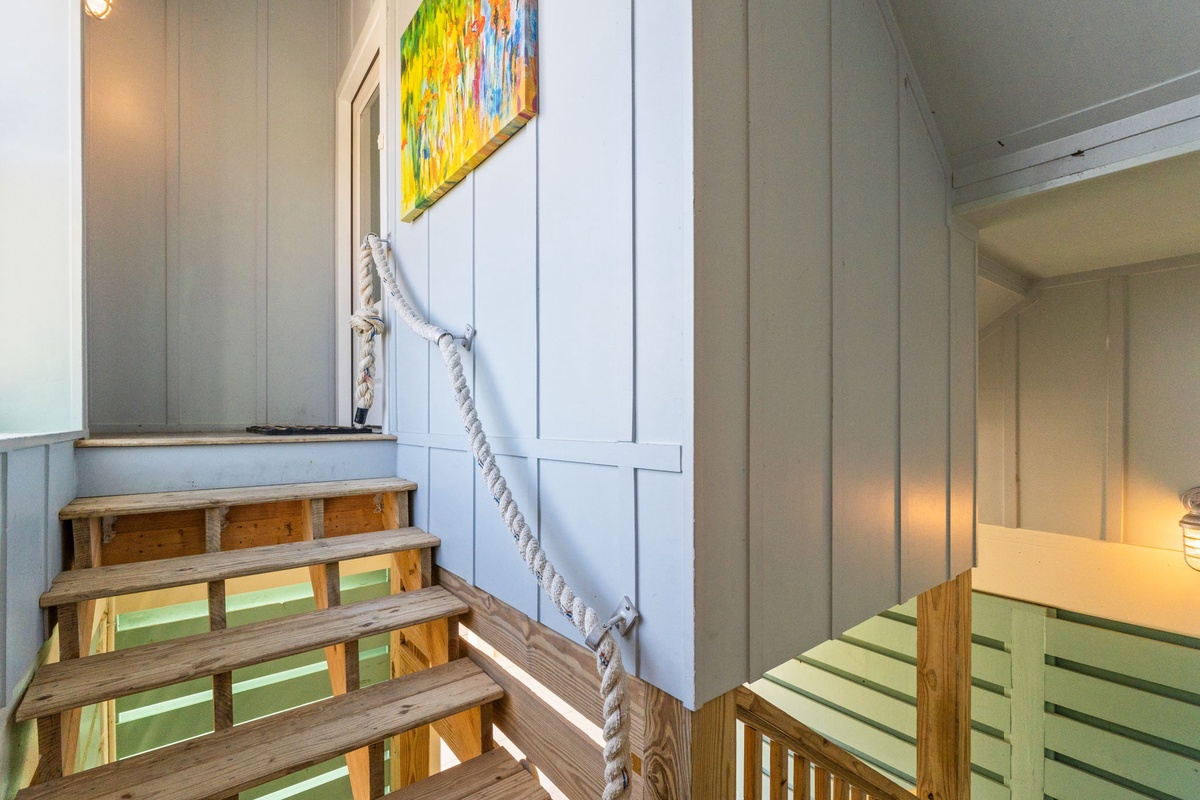 Climb the charming wooden stairs to your upper level retreat, where colorful artwork and rope railings add coastal character to your stay.