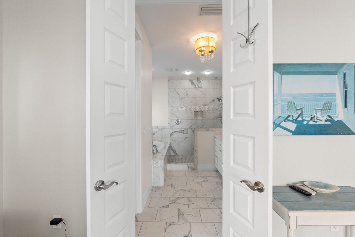 Your luxurious marble bathroom awaits with elegant fixtures and a stunning chandelier overhead.