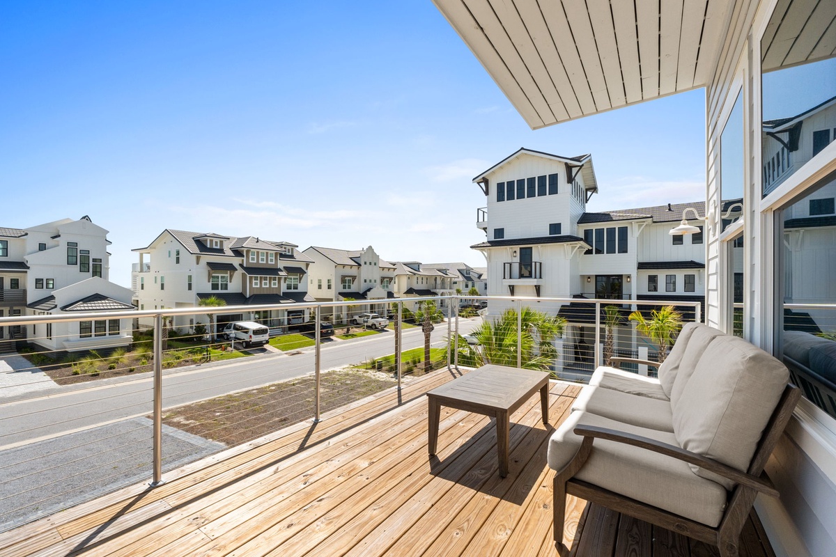 Step onto your private balcony with wood decking and sleek glass railings, where comfortable seating invites you to relax and soak in the coastal neighborhood views. Perfect for morning coffee or evening unwinding in the fresh air.