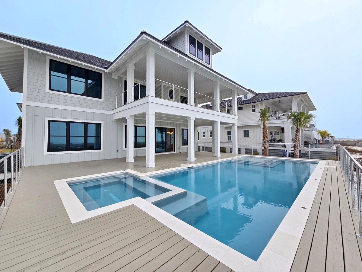 Modern beachfront property featuring a pristine swimming pool and spa, surrounded by elegant coastal architecture and palm trees.