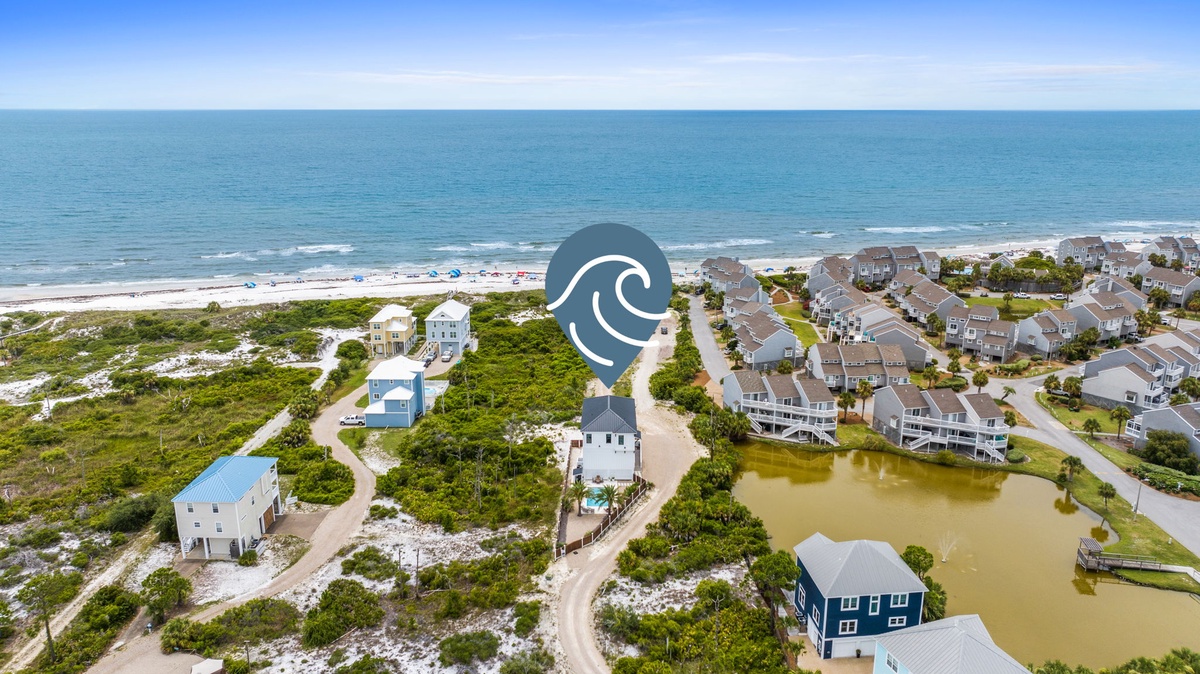 Aerial view of a coastal residential community nestled between the ocean and inland waterways, featuring beachfront properties and nearby shoreline access.