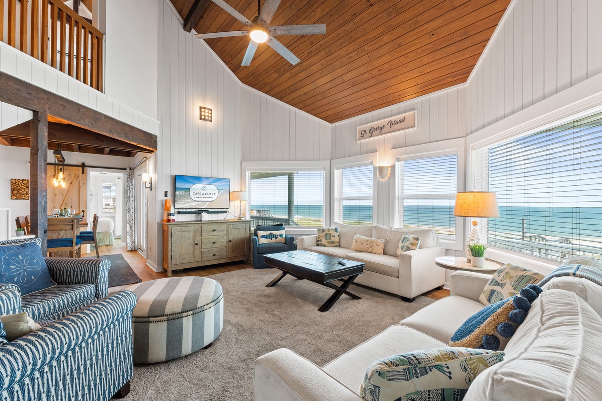 Unwind in your bright, beachy living space with soaring vaulted wood ceilings, plush seating, and stunning ocean views just beyond the windows.
